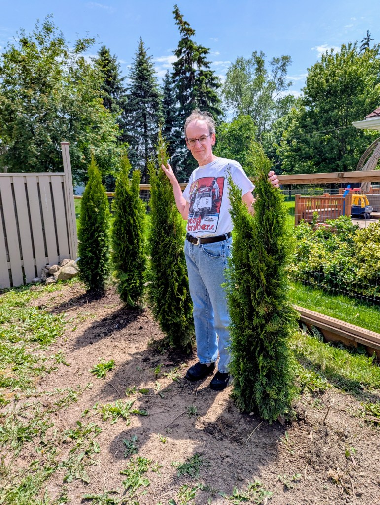 Me standing next to the trees we planted next to the driveway - June 5 2026